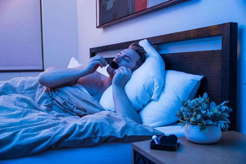 Man lying in bed applying Hostage Tape mouth strip for better sleep and breathing