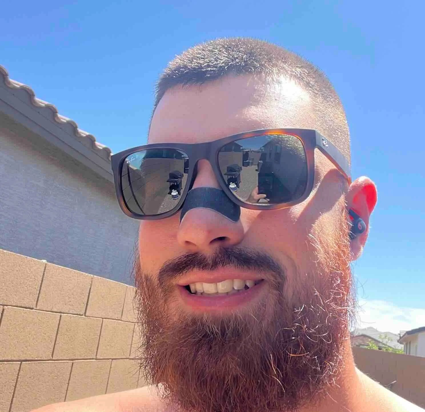 Man wearing sunglasses with a clear blue sky and house in the background
