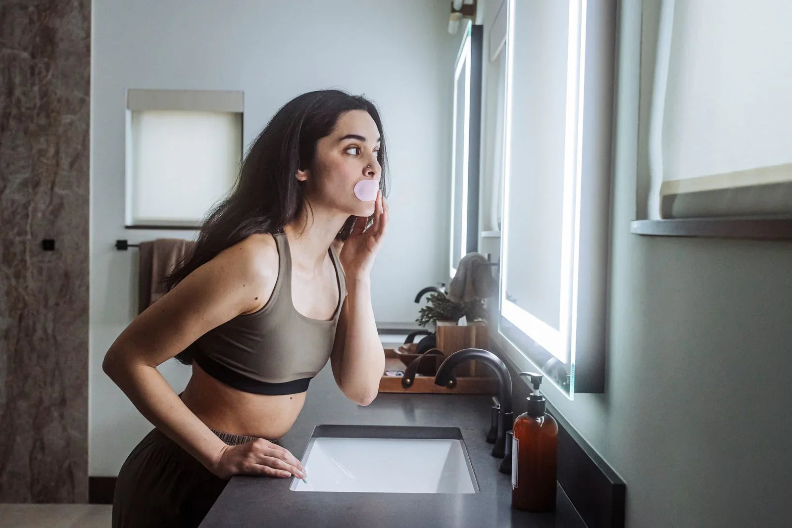 Woman applying pink Hostage Mouth Tape, medically approved for better sleep and nasal breathing