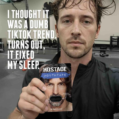 Man in gym holding Hostage Mouth Tape package for improved sleep
