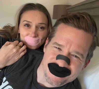 Man and woman sleeping with Hostage Mouth Tape, pink and black, and Nose Strips
