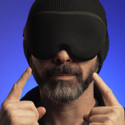 Man wearing black sleep mask pointing at his eyes with Hostage Tape