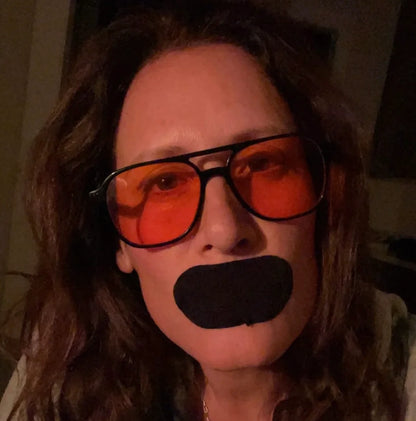 Woman with red glasses wearing Hostage Mouth Tape for better sleep and nasal breathing